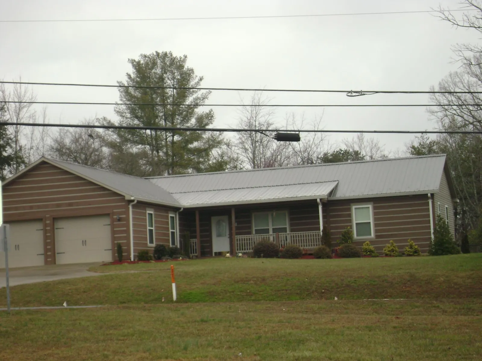 Gray metal roof on a log sided ranch home with a front porch in Malaga