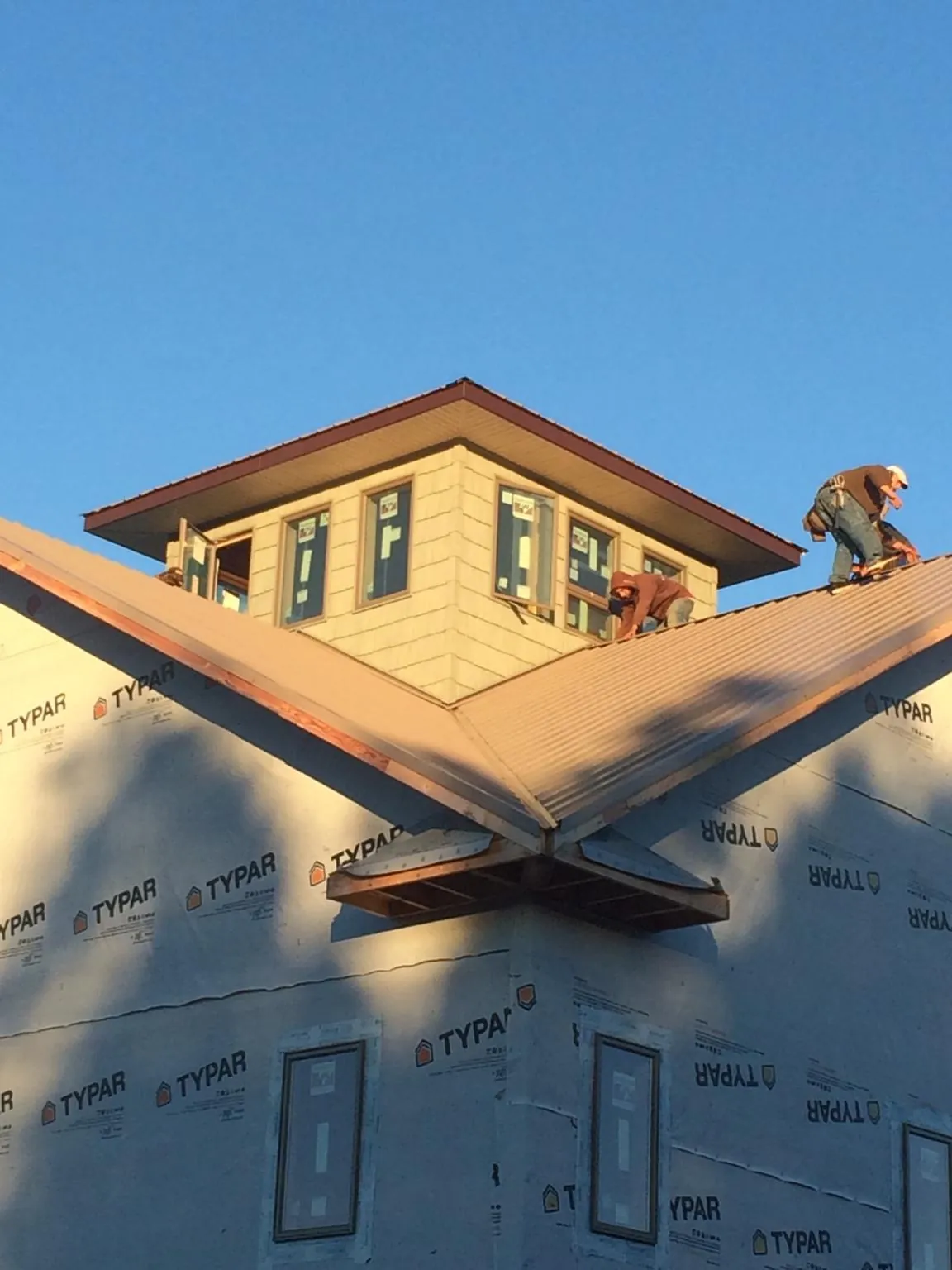Roofers working around a rooftop cupola on a new metal roof at sunset — Roof Waterproofing in Malaga by Roofing Brothers